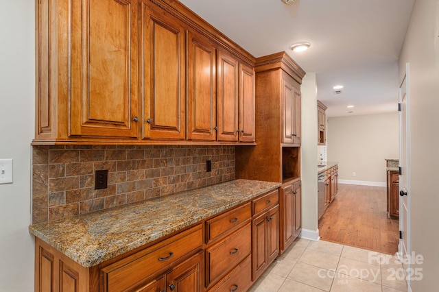 2817 Long Cir Unit 1, Iron Station, NC 28080 - kitchen with brown cabinetry, dark stone counters, light tile patterned flooring, and decorative backsplash