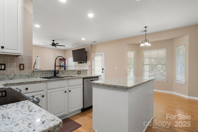 4764 Brockton Ct NW, Concord, NC 28027 - kitchen with stainless steel dishwasher, a sink, a peninsula, backsplash, and white cabinets