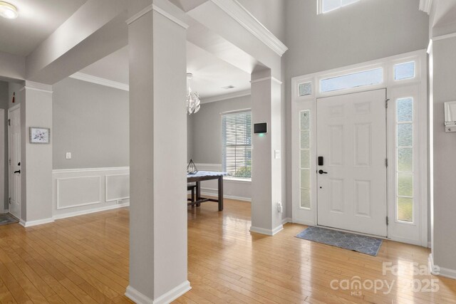 4764 Brockton Ct NW, Concord, NC 28027 - entryway featuring decorative columns, light wood finished floors, crown molding, a chandelier, and baseboards