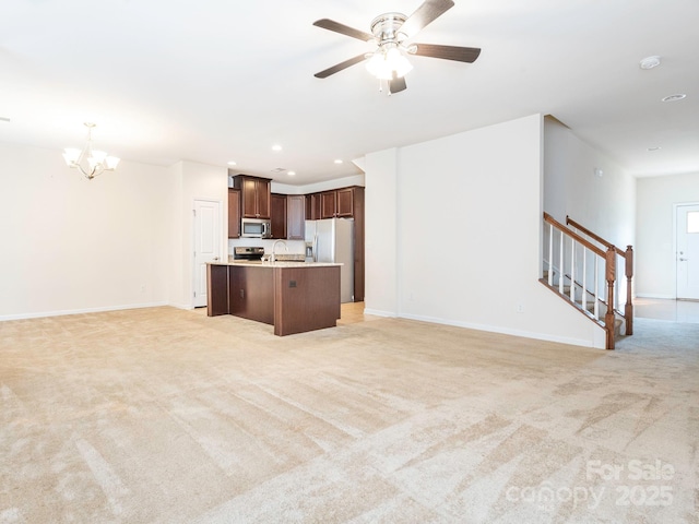 709 Volta Dr NW, Concord, NC 28027 - unfurnished living room featuring a chandelier, light colored carpet, a sink, stairs, and a ceiling fan