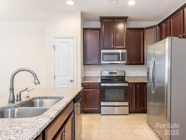 709 Volta Dr NW, Concord, NC 28027 - kitchen with stainless steel appliances, a sink, recessed lighting, light stone countertops, and dark brown cabinetry
