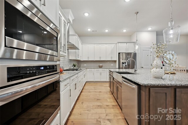 10022 Wayfair Meadow Ct, Charlotte, NC 28277 - kitchen featuring stainless steel appliances, a sink, light wood-style flooring, white cabinetry, and tasteful backsplash