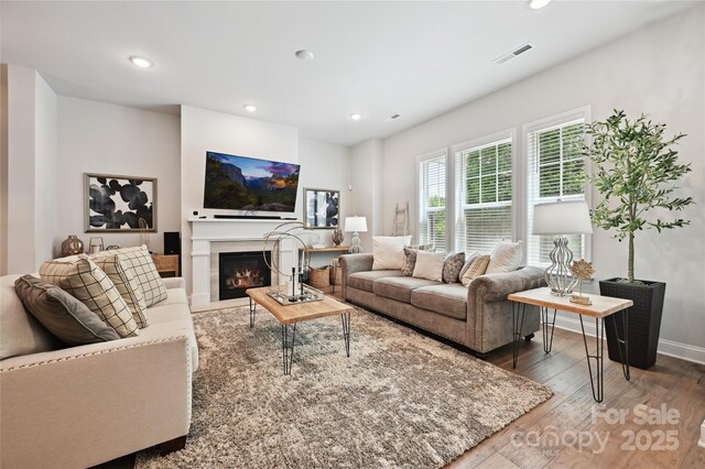 10022 Wayfair Meadow Ct, Charlotte, NC 28277 - living room featuring wood finished floors, recessed lighting, a warm lit fireplace, and baseboards