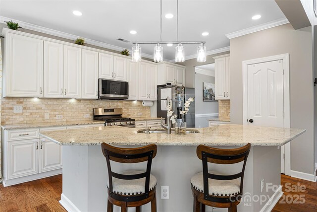 12312 Mcallister Park Dr, Charlotte, NC 28277 - kitchen featuring appliances with stainless steel finishes, dark wood finished floors, an island with sink, white cabinets, and tasteful backsplash