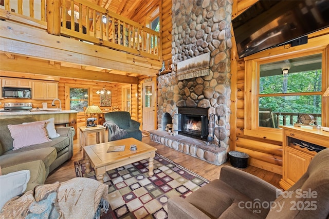 536 Tawodi Trl, Maggie Valley, NC 28751 - living area with rustic walls, plenty of natural light, wood finished floors, a stone fireplace, and a towering ceiling