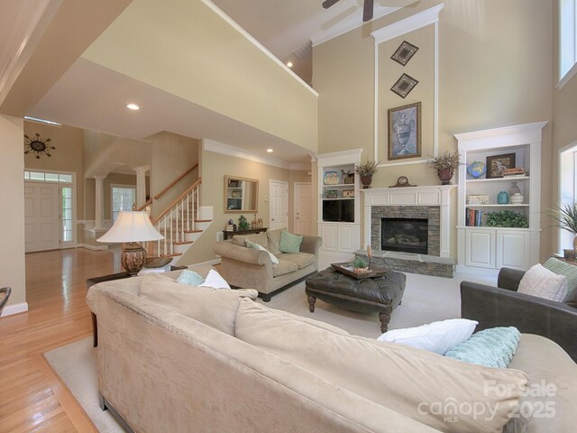 155 Culpeze Rd, Mooresville, NC 28117 - living room featuring stairway, a high ceiling, a stone fireplace, light wood finished floors, and plenty of natural light