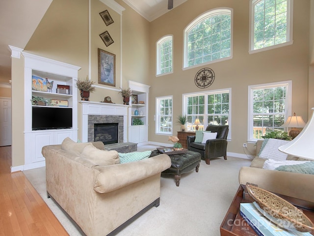 155 Culpeze Rd, Mooresville, NC 28117 - living room featuring a high ceiling, crown molding, a stone fireplace, built in shelves, and light wood-style flooring