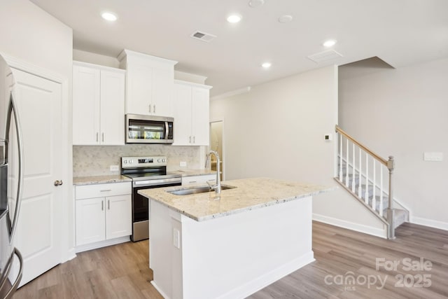 1423 Old Rivers Rd, Concord, NC 28027 - kitchen with stainless steel appliances, a sink, a center island with sink, light wood-style floors, and backsplash