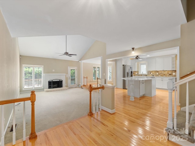 5104 Top Seed Ct, Charlotte, NC 28226 - unfurnished living room with a ceiling fan, light wood finished floors, a brick fireplace, and lofted ceiling
