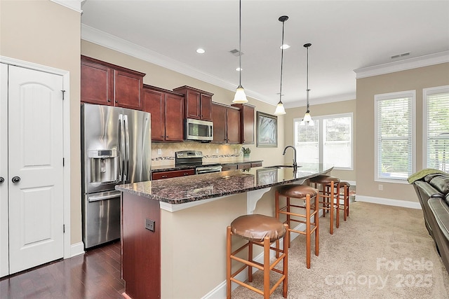 1397 Tupelo Rd, Clover, SC 29710 - kitchen featuring appliances with stainless steel finishes, ornamental molding, a center island with sink, a kitchen breakfast bar, and dark stone counters
