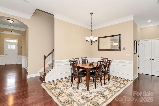 1397 Tupelo Rd, Clover, SC 29710 - dining room with arched walkways, dark wood-type flooring, stairs, wainscoting, and a chandelier