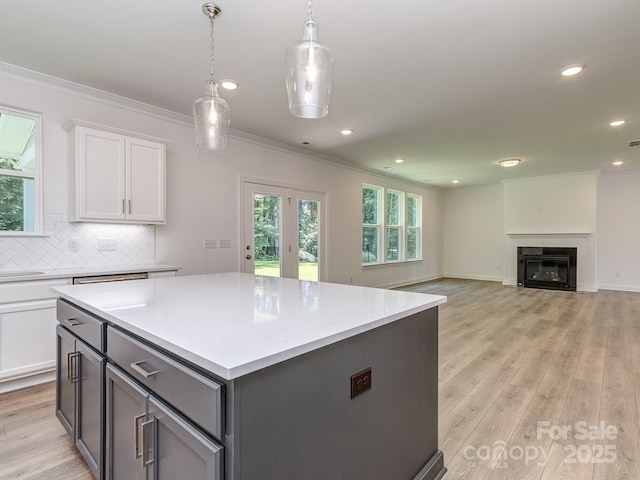 7108 Hambright Rd, Huntersville, NC 28078 - kitchen featuring ornamental molding, white cabinets, light countertops, light wood-style floors, and tasteful backsplash