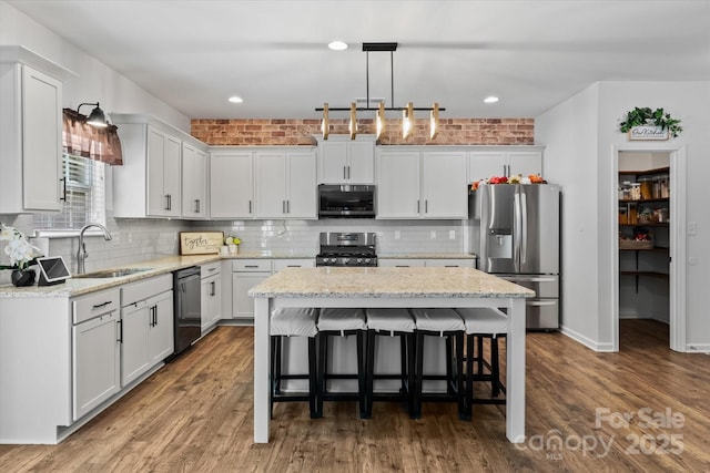 301 Wheat Field Dr, Mount Holly, NC 28120 - kitchen featuring appliances with stainless steel finishes, a sink, a center island, a kitchen bar, and backsplash