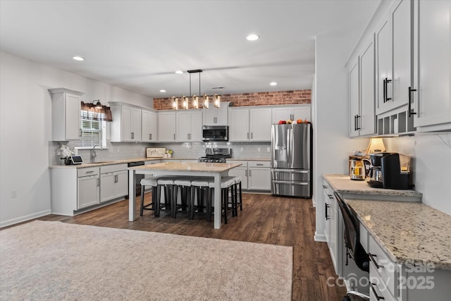 301 Wheat Field Dr, Mount Holly, NC 28120 - kitchen with stainless steel appliances, a sink, a kitchen breakfast bar, a center island, and backsplash