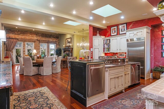 231 N Main St, Hendersonville, NC 28792 - kitchen with a skylight, dark wood finished floors, appliances with stainless steel finishes, an island with sink, and recessed lighting