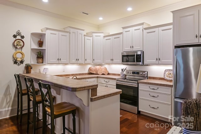 231 N Main St, Hendersonville, NC 28792 - kitchen featuring appliances with stainless steel finishes, open shelves, a peninsula, a breakfast bar, and tile counters
