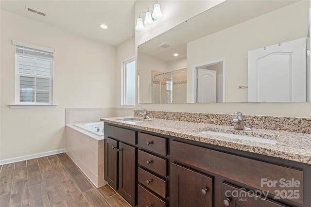 966 NW Parkland Pl, Concord, NC 28027 - bathroom featuring double vanity, a garden tub, wood finished floors, a tile shower, and baseboards