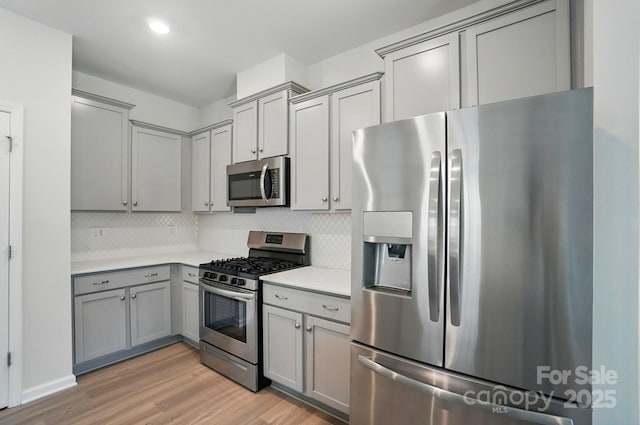 5334 Orchid Bloom Dr, Fort Mill, SC 29707 - kitchen featuring appliances with stainless steel finishes, gray cabinets, light wood-type flooring, light countertops, and tasteful backsplash