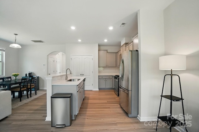 5334 Orchid Bloom Dr, Fort Mill, SC 29707 - kitchen featuring stainless steel appliances, a sink, arched walkways, gray cabinetry, and light wood-style flooring
