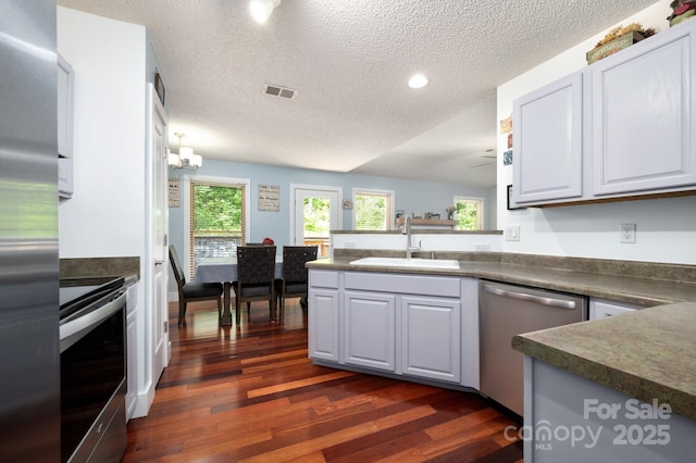 178 Susanna Cove Rd, Mars Hill, NC 28754 - kitchen featuring appliances with stainless steel finishes, a peninsula, dark wood finished floors, dark countertops, and a textured ceiling