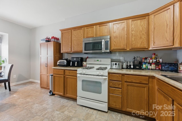 158 Snead Rd, Fort Mill, SC 29715 - kitchen with white gas range oven, stainless steel microwave, light countertops, and brown cabinetry