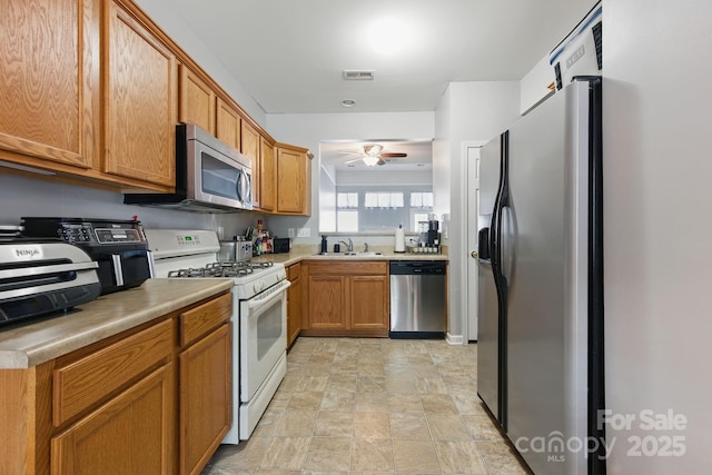 158 Snead Rd, Fort Mill, SC 29715 - kitchen featuring appliances with stainless steel finishes, a ceiling fan, stone finish floors, light countertops, and brown cabinets