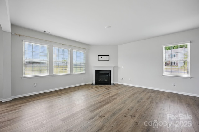 223 Haddonsfield Dr, Mooresville, NC 28115 - unfurnished living room featuring healthy amount of natural light, wood finished floors, a glass covered fireplace, and baseboards