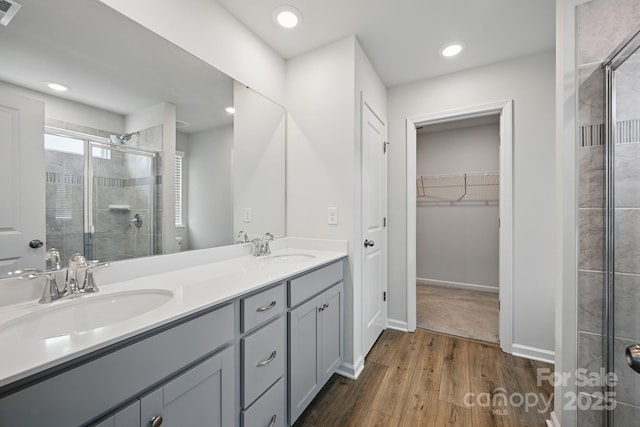 223 Haddonsfield Dr, Mooresville, NC 28115 - bathroom featuring a shower stall, wood finished floors, double vanity, a spacious closet, and recessed lighting