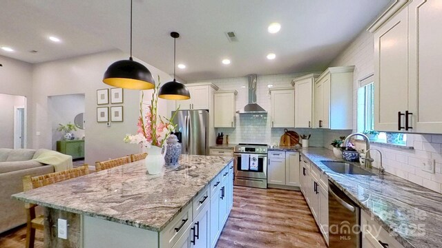 3633 Longpond Ln, Monroe, NC 28110 - kitchen with appliances with stainless steel finishes, wall chimney exhaust hood, a sink, wood finished floors, and light stone countertops