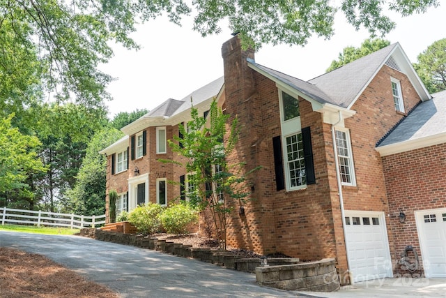 315 Red Barn Trl, Matthews, NC 28104 - view of property exterior with a chimney, asphalt driveway, brick siding, a garage, and roof with shingles