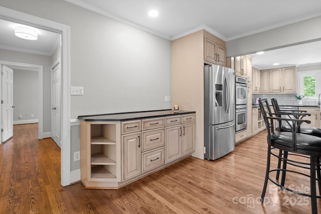 315 Red Barn Trl, Matthews, NC 28104 - kitchen featuring appliances with stainless steel finishes, light wood-type flooring, cream cabinetry, decorative backsplash, and dark countertops