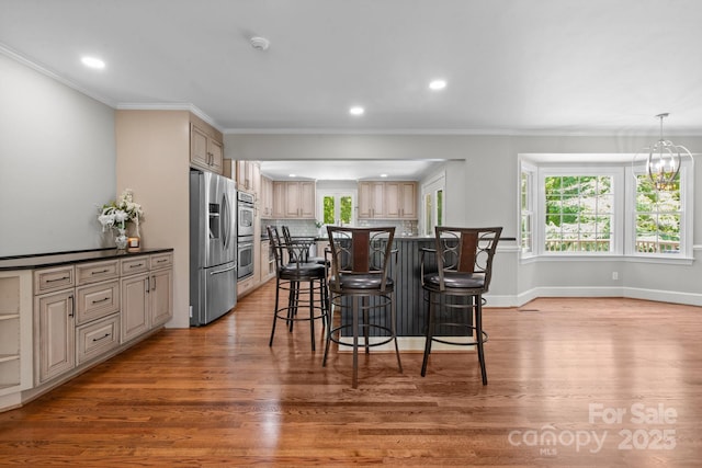 315 Red Barn Trl, Matthews, NC 28104 - kitchen with appliances with stainless steel finishes, a kitchen bar, light wood-type flooring, recessed lighting, and crown molding