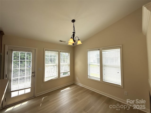 1423 Napa St NW, Concord, NC 28027 - unfurnished dining area with a chandelier, wood finished floors, lofted ceiling, and baseboards