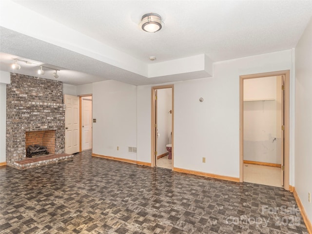 51 Wake Robin Way, Asheville, NC 28805 - unfurnished living room with baseboards, a fireplace, track lighting, and a textured ceiling