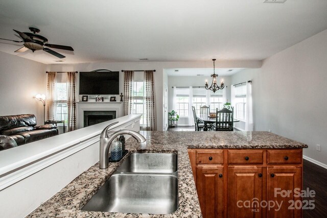 107 Golden Valley Dr, Mooresville, NC 28115 - kitchen featuring open floor plan, a sink, brown cabinets, a fireplace, and a chandelier