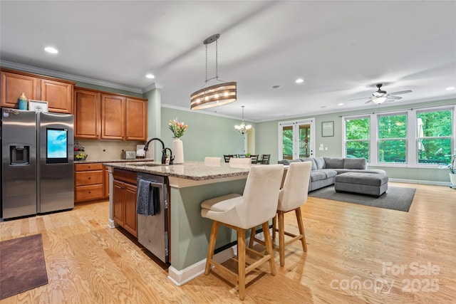 137 Leaning Tower Dr, Mooresville, NC 28117 - kitchen featuring stainless steel appliances, a sink, light wood-style floors, ornamental molding, and brown cabinets