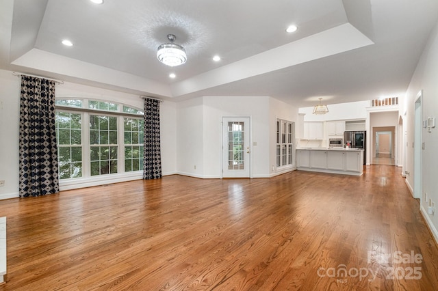 6823 Manatee Dr, Concord, NC 28025 - unfurnished living room featuring a raised ceiling, light wood-style floors, baseboards, and recessed lighting