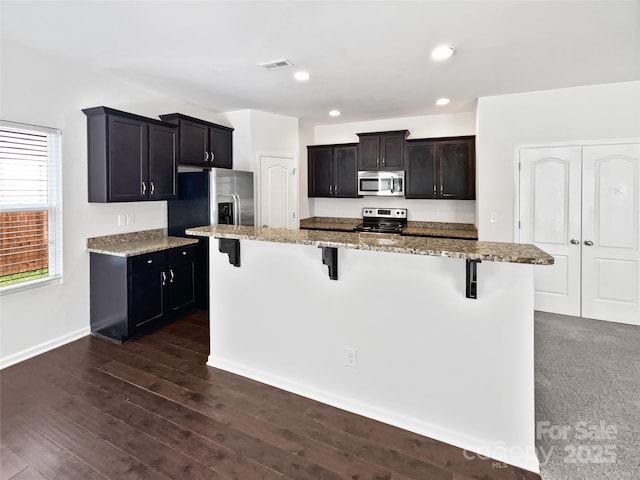 108 Greenway View Ct, Mount Holly, NC 28120 - kitchen featuring stainless steel appliances, a kitchen bar, light stone counters, dark wood-type flooring, and recessed lighting