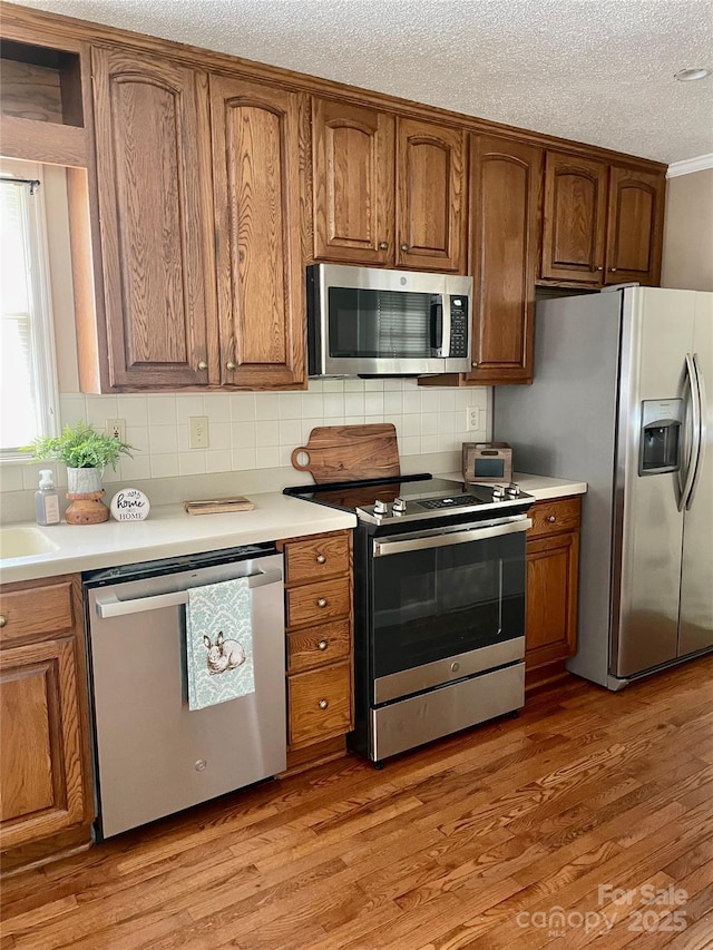 218 Hardin Cir, Grover, NC 28073 - kitchen with stainless steel appliances, brown cabinetry, tasteful backsplash, a textured ceiling, and ornamental molding