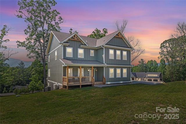 17 Baxter Woods Ln, Candler, NC 28715 - back of house at dusk featuring a yard, covered porch, board and batten siding, and a shingled roof