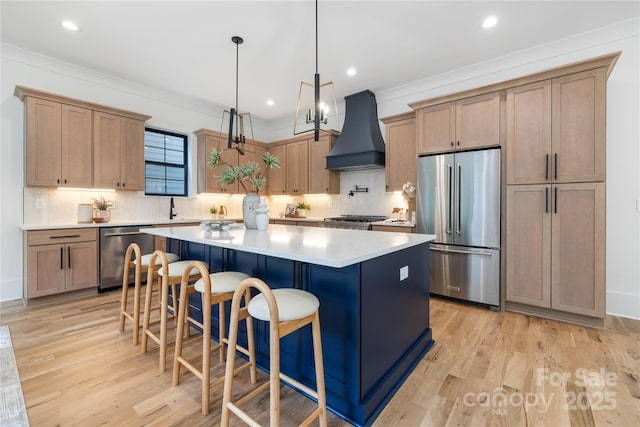3903 Plainview Rd, Charlotte, NC 28208 - kitchen with appliances with stainless steel finishes, custom exhaust hood, a kitchen island, light wood-style floors, and crown molding