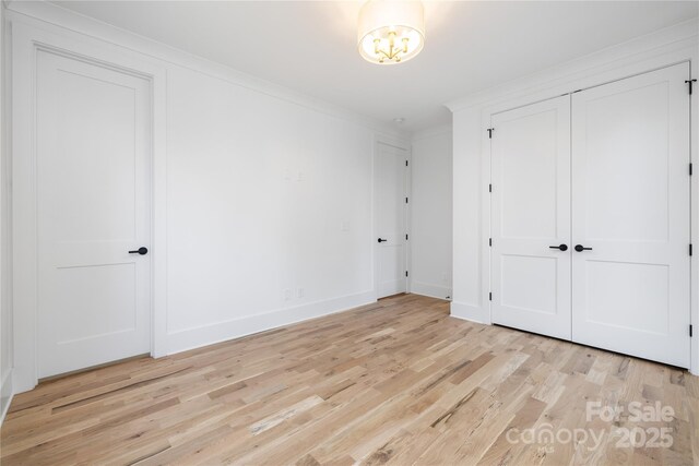 3903 Plainview Rd, Charlotte, NC 28208 - unfurnished bedroom featuring light wood-style floors, crown molding, baseboards, a chandelier, and a closet