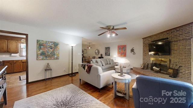 4920 Surfwood Dr, Sherrills Ford, NC 28673 - living room featuring a ceiling fan, light wood-style flooring, baseboards, and a fireplace