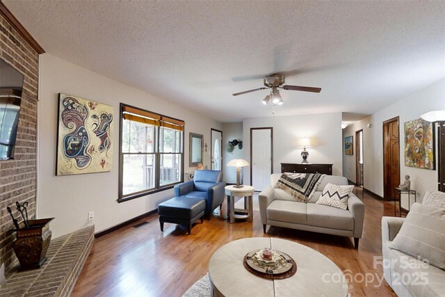 4920 Surfwood Dr, Sherrills Ford, NC 28673 - living area featuring wood finished floors, a ceiling fan, a textured ceiling, baseboards, and a brick fireplace