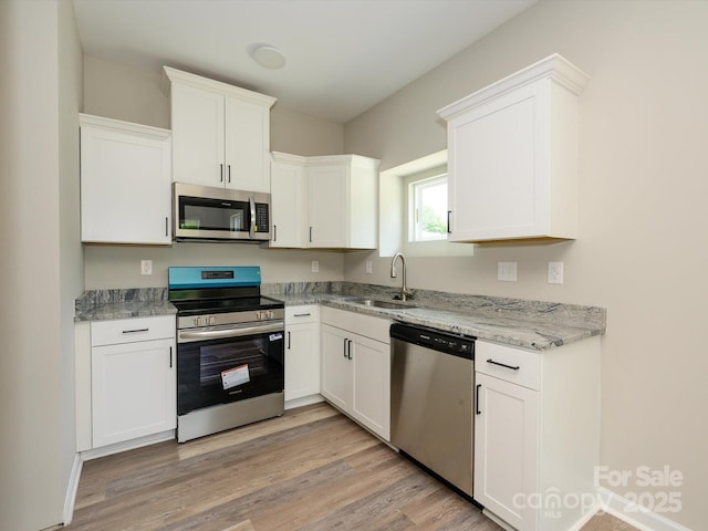 614 Kings Mountain St, Clover, SC 29710 - kitchen featuring appliances with stainless steel finishes, white cabinetry, light wood-style flooring, and light stone countertops