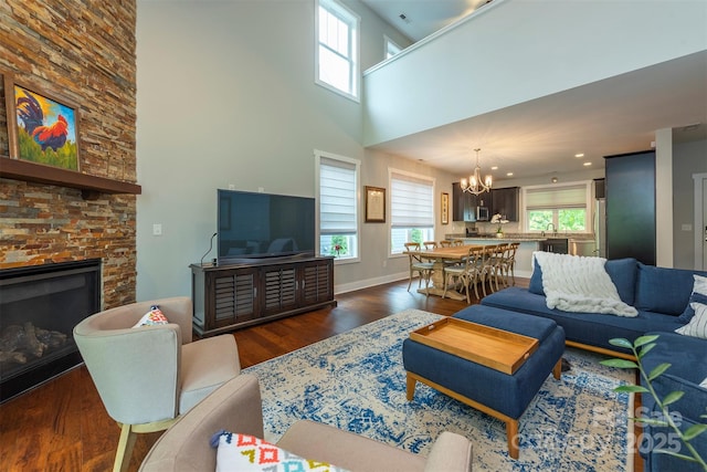 253 Flat Creek Rd, Black Mountain, NC 28711 - living room with a chandelier, dark wood-style flooring, a stone fireplace, a towering ceiling, and baseboards