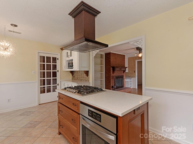 3408 Oak Tree Trl, Matthews, NC 28105 - kitchen with stainless steel appliances, island range hood, ceiling fan, a chandelier, and light tile patterned floors