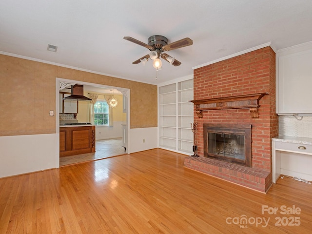 3408 Oak Tree Trl, Matthews, NC 28105 - unfurnished living room featuring a ceiling fan, wood finished floors, a brick fireplace, ornamental molding, and built in shelves