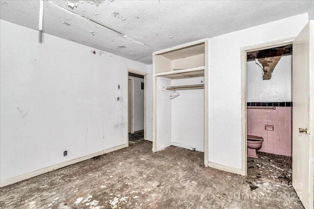 714 Pine St, Hamlet, NC 28345 - unfurnished bedroom with tile walls, a closet, connected bathroom, and a textured ceiling