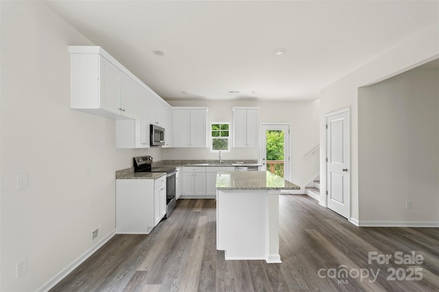 510 3rd St, Salisbury, NC 28144 - kitchen featuring appliances with stainless steel finishes, a kitchen island, dark wood-style floors, white cabinetry, and light stone counters